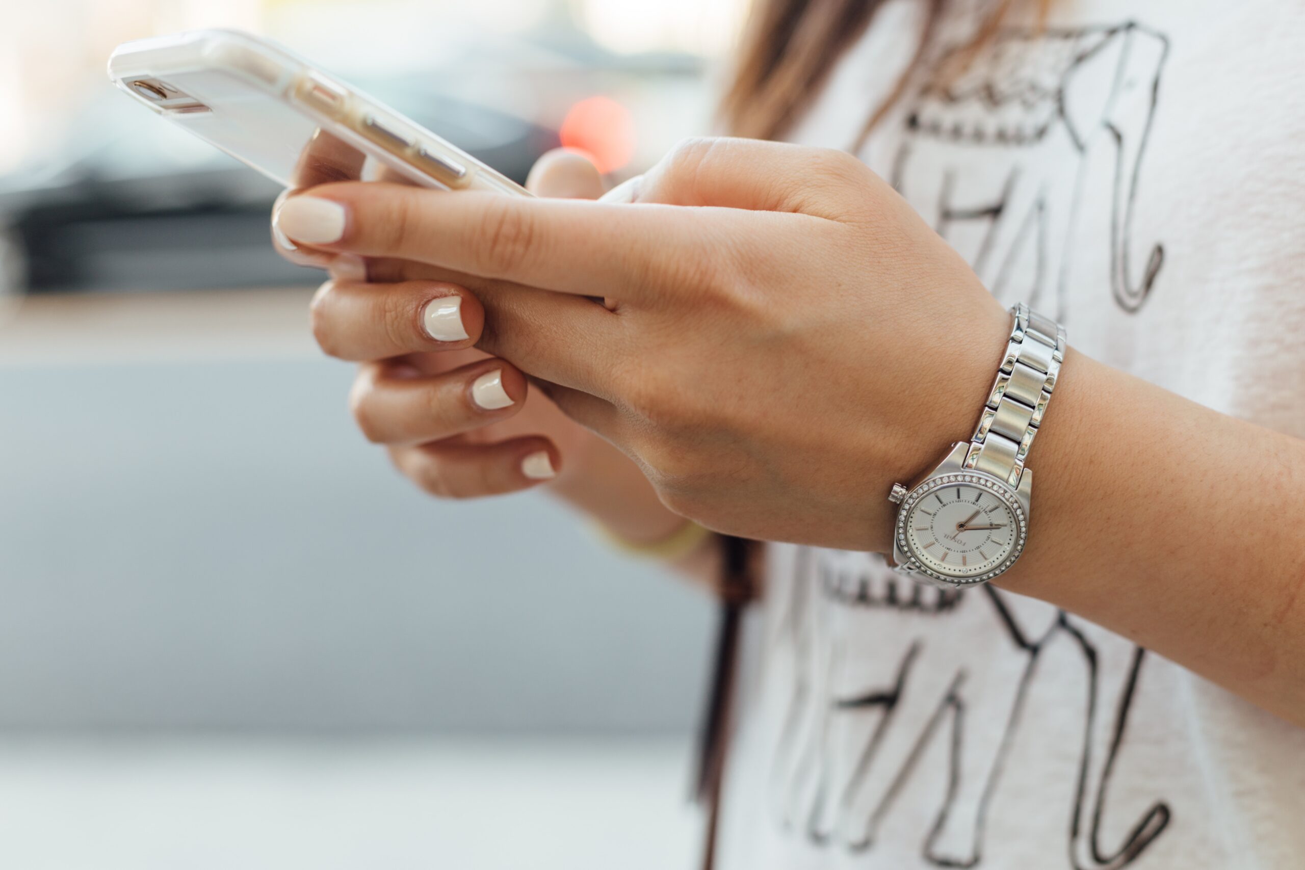 close up photo of woman wearing watch holding a mobile device in her hands