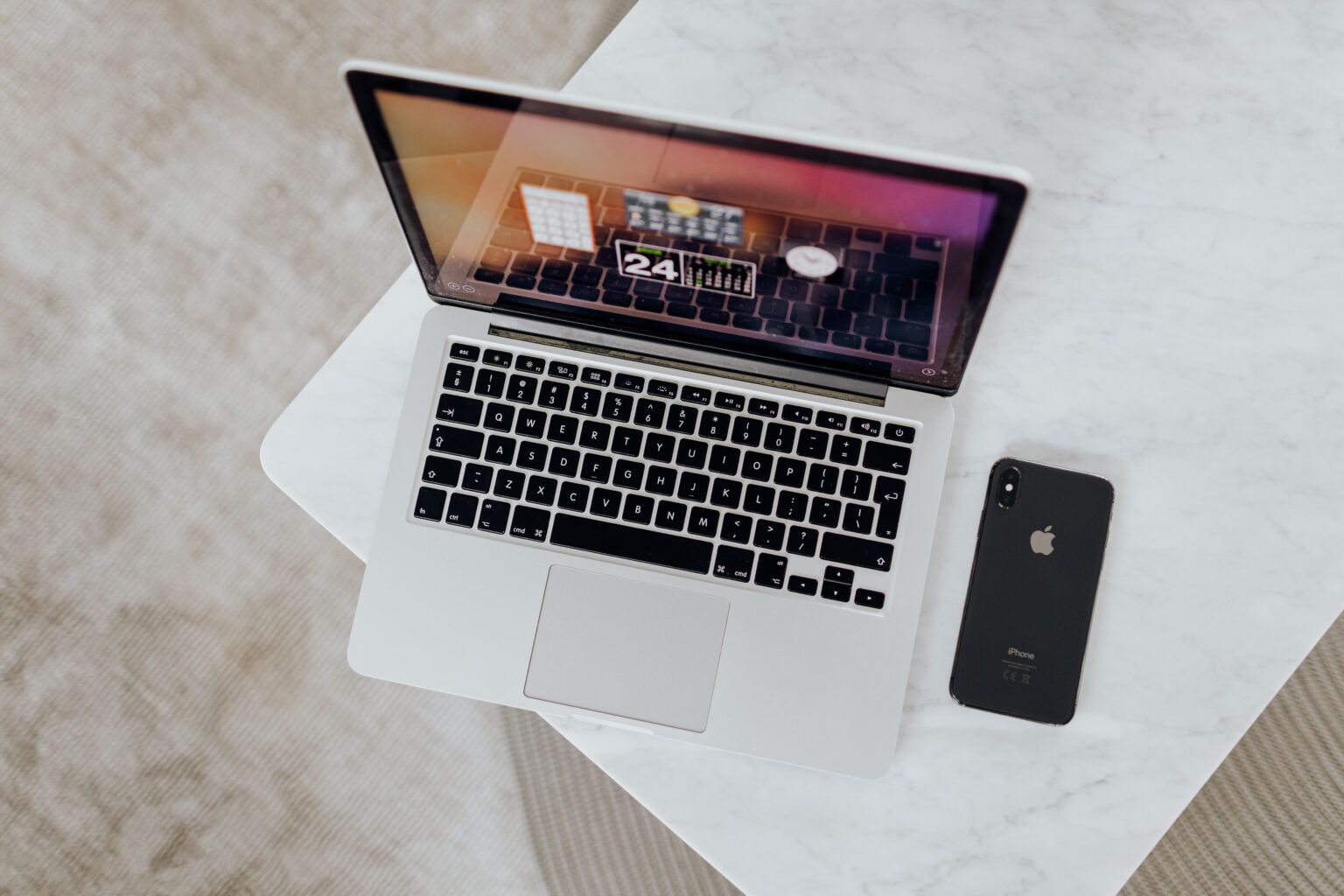Open MacBook on table next to black iPhone