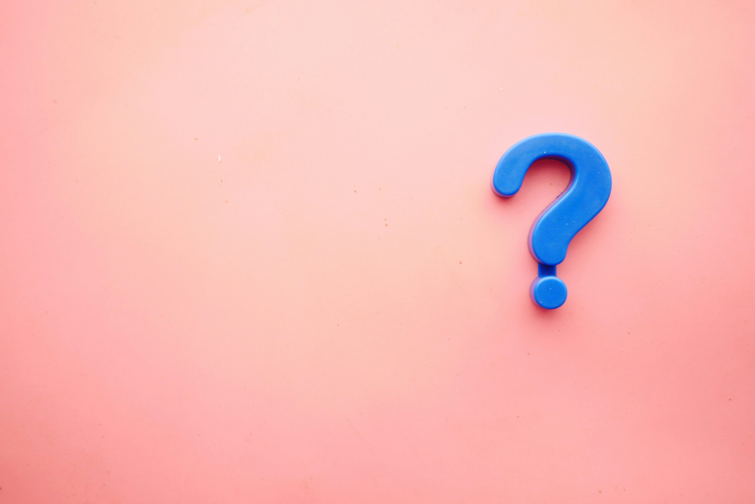 a blue question mark stands out against a light pink background signaling how to choose between showit template customization and fully custom design